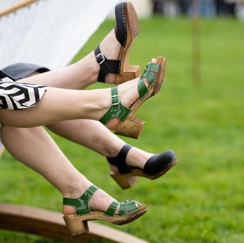 Frauenbeine mit Clogs auf grüner Wiese